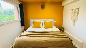 Un dormitorio con una cama con paredes amarillas y una ventana. en Studio Wellness & Détente Cosy, en Maubec