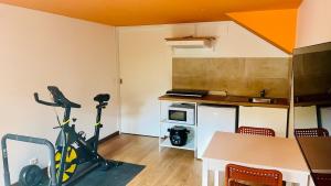 Una cocina con una bicicleta estática y una mesa en una habitación. en Studio Wellness & Détente Cosy, en Maubec