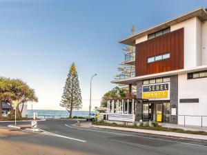 a building on a street with the ocean in the background at The Sebel Brisbane Margate Beach in Redcliffe