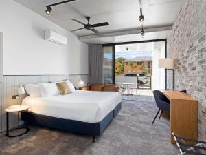 a bedroom with a bed and a brick wall at The Sebel Brisbane Margate Beach in Redcliffe