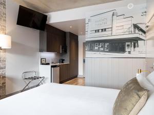 a bedroom with a white bed and a kitchen at The Sebel Brisbane Margate Beach in Redcliffe