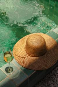 a straw hat and a glass of wine in a swimming pool at Amana Icaraizinho in Amontada