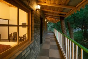a porch of a house with a table and a chair at Heyan Cedar Woods Nainital in Nainital