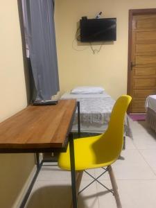 a yellow chair in a room with a desk and a bed at Hotel Arara Azul in Pontes e Lacerda +16 photos