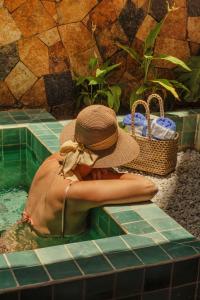 a woman in a hat sitting in a swimming pool at Amana Icaraizinho in Amontada