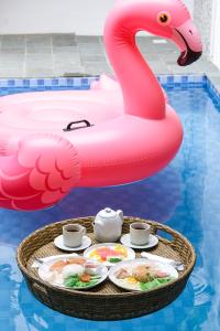 un plateau de nourriture sur un flamant rose dans une piscine dans l'établissement Sampai Villa Jumpa, à Balong