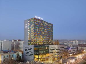 Un edificio alto con un cartel encima. en Novotel Ulaanbaatar, en Ulán Bator