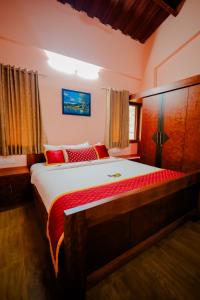 a bedroom with a large bed with red pillows at Anvitha Mansions in Attigundi