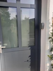 una porta di vetro con il riflesso di una persona al suo interno di Le cottage , logement individuel de plain pied a Villeneuve d'Ascq
