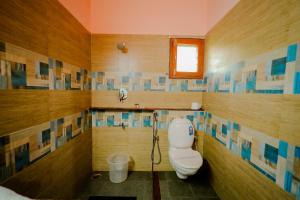 a bathroom with a toilet and a window at Anvitha Mansions in Attigundi +46 photos
