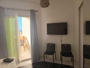 une pièce avec deux chaises, une télévision et un balcon dans l'établissement Royal Beach Resort, à Hurghada