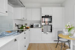 a white kitchen with white cabinets and a table at Morford House - Stylish Retreat in the Heart of Exeter in Exeter