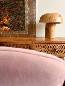 a wooden dresser with a painting and a pink chair at City Solei Boutique Hotel in Poznań