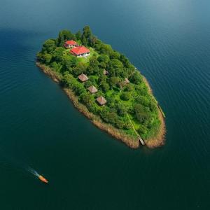 an island in the water with a house on it at Sharp Island Gorilla Lodge, Lake Bunyonyi in Kashasha