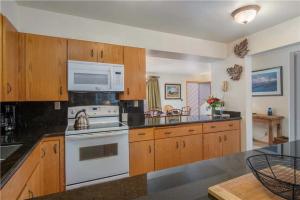 a kitchen with white appliances and wooden cabinets at RMR: Wind River 5 Condo in Teton Village in Teton Village