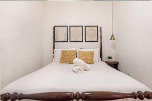 une chambre avec un grand lit blanc avec des oreillers jaunes dans l'établissement SDQ Colonial Zone an great find, à Saint-Domingue