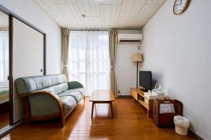 a living room with a couch and a tv at Enoshima Apartment Hotel in Fujisawa