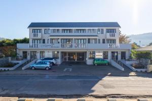 a large white building with two cars parked in a parking lot at Oceans Deep at Lagoon Terrace - Knysna! in Knysna
