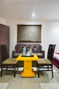 a yellow table with two chairs and a tea kettle on it at Hotel Kelvish With Free Airport Pickup in New Delhi