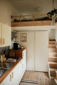 a kitchen with white cabinets and a staircase at Tiny House Alba - ervaar tiny house living in Diessen