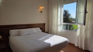 a bedroom with a white bed and a window at Hotel Las Moreras in León