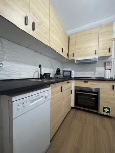 een keuken met houten kasten en een witte vaatwasser bij Apartamento Central Rainha in Caldas da Rainha