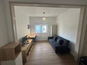 een woonkamer met een blauwe bank en een tafel bij Apartamento Central Rainha in Caldas da Rainha