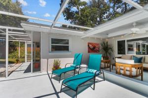 un patio con sillas azules y una mesa en Madeira Beach Pool Home with Guest House, en San Petersburgo