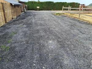 een lege weg met een hek en een huis bij La jonquiere camping in Landouzy-la-Cour