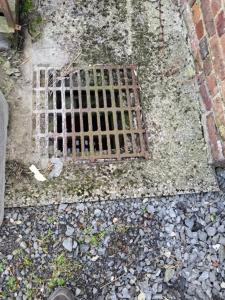 een metalen rooster in de grond naast een gebouw bij La jonquiere camping in Landouzy-la-Cour