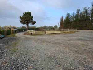 een onverharde weg met een hek en een boom bij La jonquiere camping in Landouzy-la-Cour