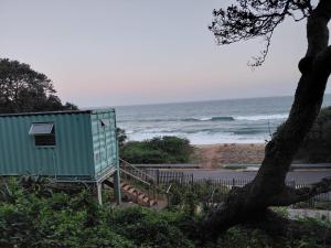 a green shack next to a beach with the ocean at uMkhaKhaya Container Home in Westbrook +3 photos