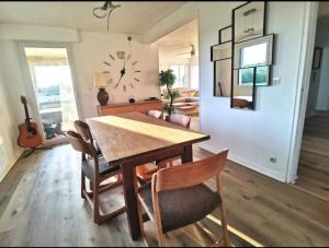 a dining room with a table and chairs and a clock at L'appart du bonheur à Reims in Jonchery-sur-Vesle