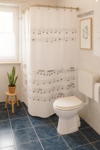 a bathroom with a sheet music shower curtain with a toilet at Ferienhaus am Neuklostersee in Neukloster