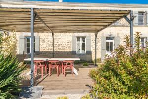 un patio con tavolo e sedie su un ponte di Les Violettes De Malleville a Saint-Romain-de-Benet Altre 37 foto
