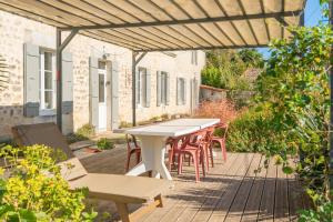 un patio con tavolo e sedie su un ponte di Les Violettes De Malleville a Saint-Romain-de-Benet