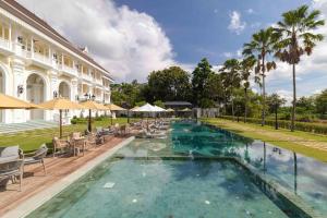 a pool with chairs and umbrellas in front of a building at Ping Pura Riverside Resort & Spa Chiang Mai in Chiang Mai +7 photos