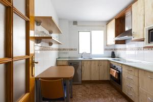 Una cocina con gabinetes de madera y una mesa de madera. en House Falucho playa, en Motril