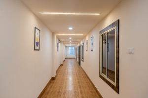 a long hallway with white walls and wooden floors and paintings at Treebo Green Olive in Rourkela
