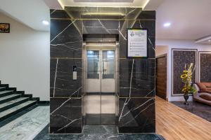 a elevator lobby with a black marble wall at Treebo Green Olive in Rourkela +38 photos