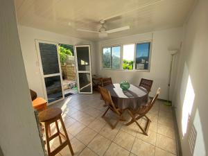 Un comedor con mesa y sillas y ventanas. en Résidence cannelle, en Les Trois-Îlets