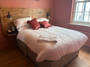 a bed with white sheets and red pillows on it at Coaching Inn in South Molton