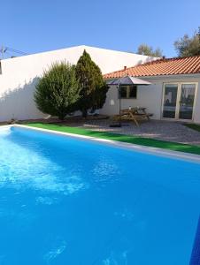 a large blue swimming pool in front of a house at Quintal do Olival- Um refúgio na Natureza in Lousã