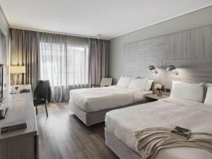 a hotel room with two beds and a desk at Pullman Santiago Vitacura in Santiago