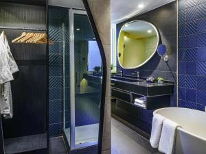 a bathroom with a tub and a mirror at Pullman Santiago El Bosque in Santiago