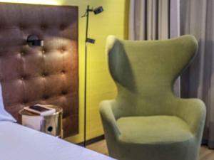 a green chair sitting at a table in a room at Pullman Santiago El Bosque in Santiago