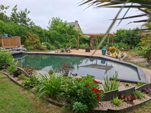 a swimming pool in a garden with plants at Gîte de la croix in La Croix-Helléan