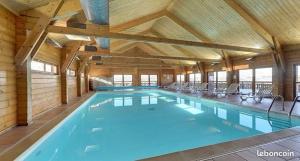 a large swimming pool in a large building at Chalet Cosy in La Joue du Loup
