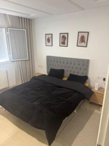 a bedroom with a large bed with a black blanket at Résidence les jasmins l''aouina in Tunis