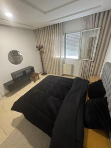 a bedroom with a large black bed and a couch at Résidence les jasmins l''aouina in Tunis